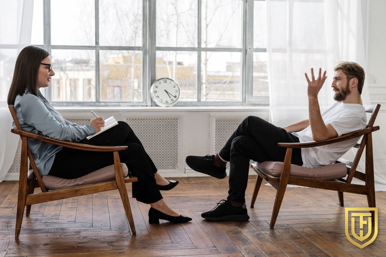 Therapist taking notes while talking with a client in a bright counseling office